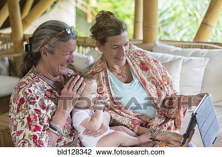 Stock Image - Caucasian family using digital tablet on patio. Fotosearch