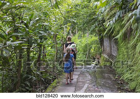 Stock Image - Caucasian family walking in tropical garden. Fotosearch