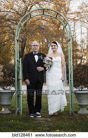Stock Image - Caucasian father walking bride down aisle. Fotosearch
