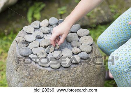 Caucasian girl arranging stones on boulder View Large Photo Image Stock Photograph - Caucasian girl arranging stones on boulder. Fotosearch