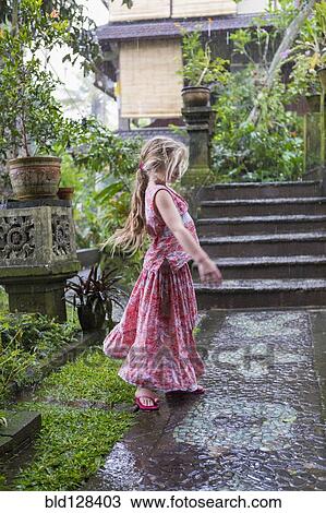 Stock Image - Caucasian girl dancing on wet patio. Fotosearch