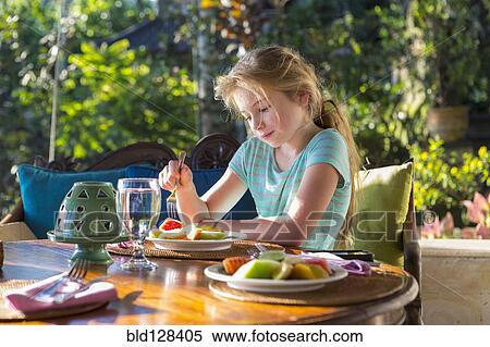 Stock Photography - Caucasian girl eating breakfast at table. Fotosearch