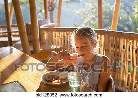 Stock Image - Caucasian girl eating on balcony. Fotosearch