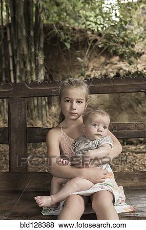 Stock Photo - Caucasian girl holding baby boy outdoors. Fotosearch