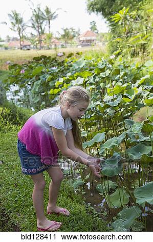 Stock Image - Caucasian girl looking a tropical plants. Fotosearch
