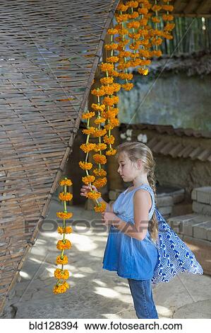 Picture - Caucasian girl looking at hanging flower strands. Fotosearch