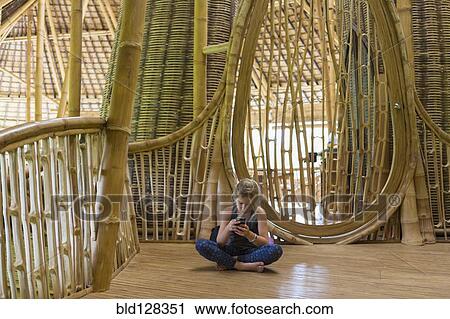 Caucasian girl using cell phone in bamboo house View Large Photo Image Stock Image - Caucasian girl using cell phone in bamboo house. Fotosearch