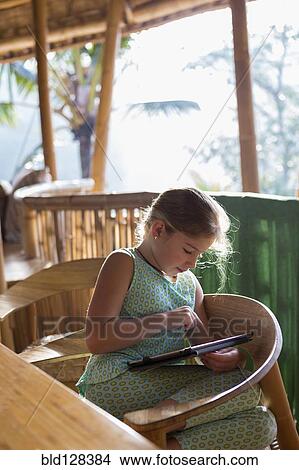 Picture - Caucasian girl using digital tablet at patio table . Fotosearch