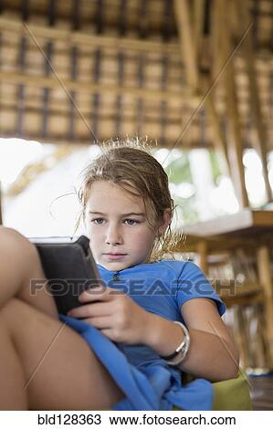 Stock Image - Caucasian girl using digital tablet on patio. Fotosearch