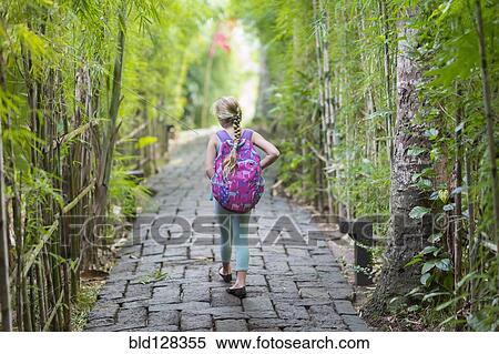 Stock Photography - Caucasian girl walking on stone path among bamboo trees. Fotosearch