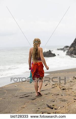 Stock Image - Caucasian girl walking on tropical beach. Fotosearch