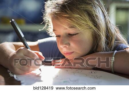 Stock Photo - Caucasian girl writing at desk. Fotosearch