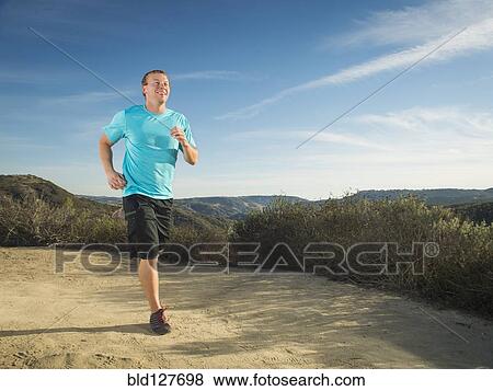 Stock Photo - Caucasian man jogging on hilltop. Fotosearch