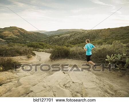 Caucasian man jogging on hilly path View Large Photo Image Stock Image - Caucasian man jogging on hilly path. Fotosearch