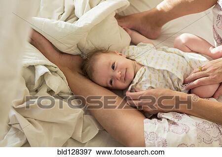 Stock Photo - Caucasian mother and baby boy laying in bed. Fotosearch