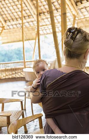 Stock Photo - Caucasian mother carrying baby boy on patio. Fotosearch