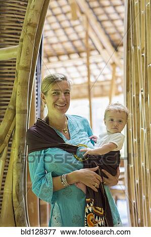 Stock Photo - Caucasian mother holding baby in bamboo doorway. Fotosearch