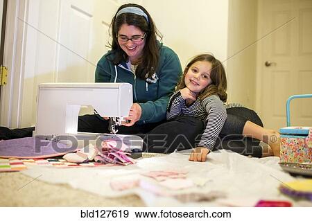 Stock Photo - Caucasian mother teaching daughter to sew. Fotosearch