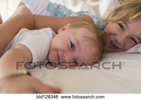 Stock Photograph - Caucasian siblings relaxing on sofa. Fotosearch