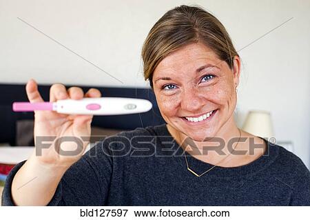 Stock Photo - Caucasian woman holding positive pregnancy test . Fotosearch