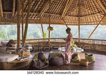 Stock Image - Caucasian woman on bamboo hotel patio. Fotosearch