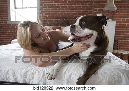 Caucasian woman petting dog on bed View Large Photo Image Stock Image - Caucasian woman petting dog on bed. Fotosearch