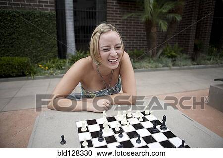 Stock Image - Caucasian woman playing chess in urban park. Fotosearch