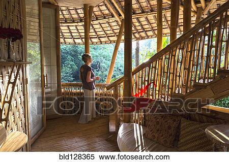 Stock Photography - Caucasian woman standing in bamboo room, Ubud, Bali, Indonesia. Fotosearch