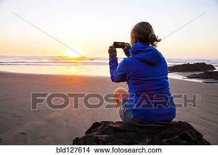 Caucasian woman taking picture of sunrise on beach View Large Photo Image Picture - Caucasian woman taking picture of sunrise on beach. Fotosearch