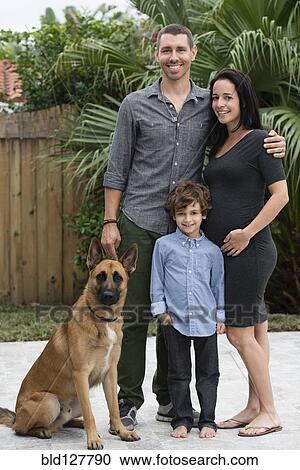 Stock Image - Family smiling together with dog outdoors. Fotosearch
