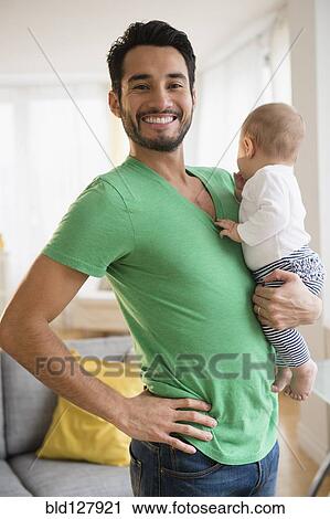 Father holding baby in living room View Large Photo Image Stock Image - Father holding baby in living room. Fotosearch