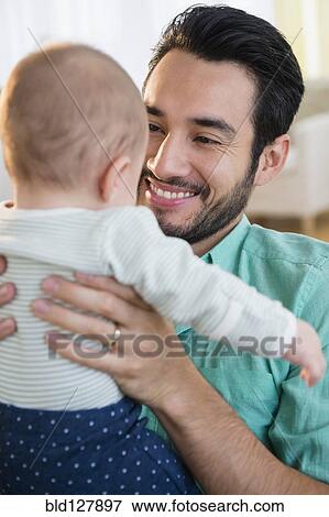 Father holding baby on sofa View Large Photo Image Stock Photo - Father holding baby on sofa. Fotosearch