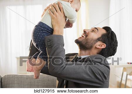Stock Photography - Father playing with baby on sofa. Fotosearch