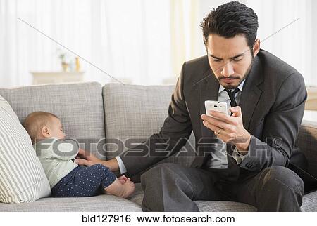 Father sitting with baby and using cell phone View Large Photo Image Stock Photograph - Father sitting with baby and using cell phone. Fotosearch