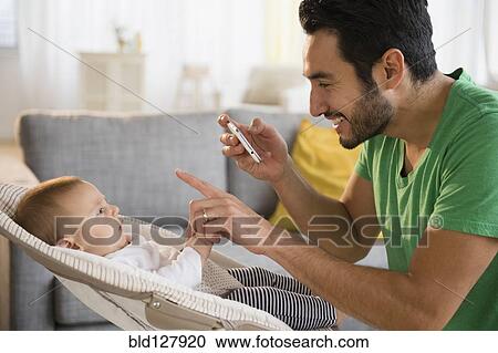 Stock Image - Father taking pictures of baby. Fotosearch