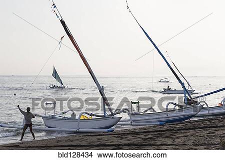 Fisherman pulling sailboat line on beach View Large Photo Image Picture - Fisherman pulling sailboat line on beach. Fotosearch