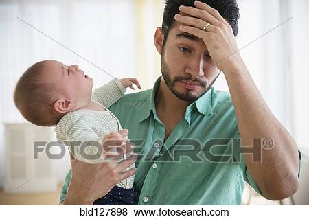 Stock Photo - Frustrated father holding crying baby. Fotosearch