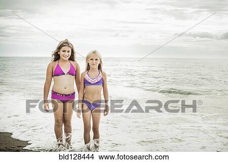 Girls smiling in waves on beach View Large Photo Image Picture - Girls smiling in waves on beach. Fotosearch