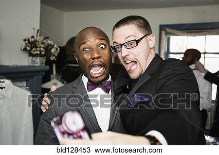 Stock Image - Groom and groomsman taking silly self-portrait. Fotosearch