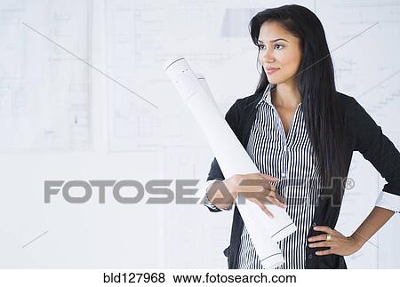 Stock Photo - Hispanic architect carrying blueprints in office. Fotosearch