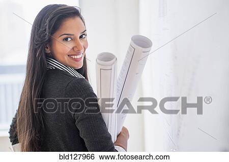 Stock Photograph - Hispanic architect carrying blueprints in office. Fotosearch