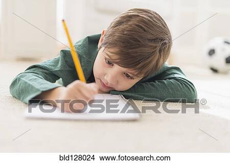 Hispanic boy doing homework on floor View Large Photo Image Picture - Hispanic boy doing homework on floor. Fotosearch