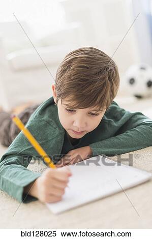 Stock Photography - Hispanic boy doing homework on floor. Fotosearch