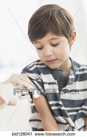 Stock Image - Hispanic boy getting a shot at doctor's office. Fotosearch