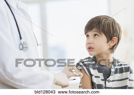 Stock Image - Hispanic boy getting a shot at doctor's office. Fotosearch