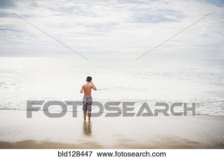 Hispanic boy standing in surf at beach View Large Photo Image Stock Photo - Hispanic boy standing in surf at beach. Fotosearch