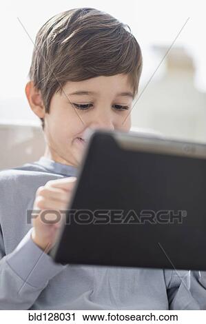Stock Image - Hispanic boy using digital tablet. Fotosearch