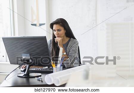 Stock Image - Hispanic businesswoman working in office. Fotosearch