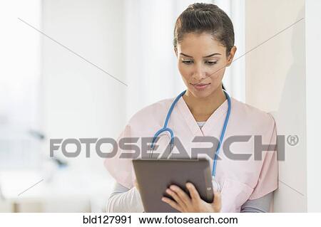 Stock Image - Hispanic nurse using digital tablet in hospital. Fotosearch