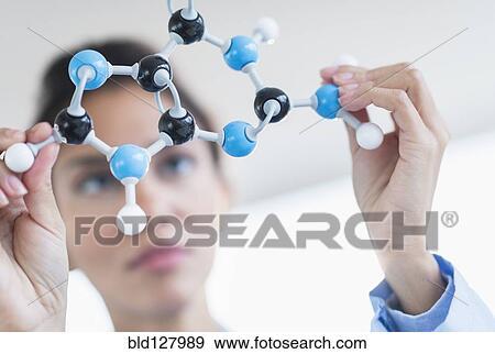 Stock Photo - Hispanic scientist examining molecular model. Fotosearch